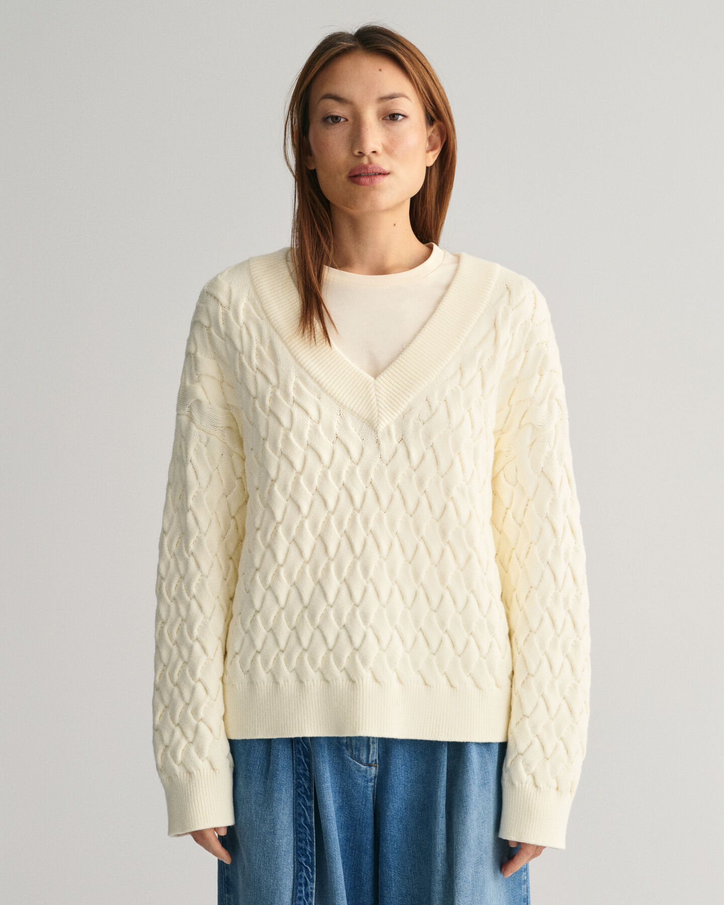 Kohopintainen puuvillaneulepusero, jossa v-p&auml;&auml;ntie