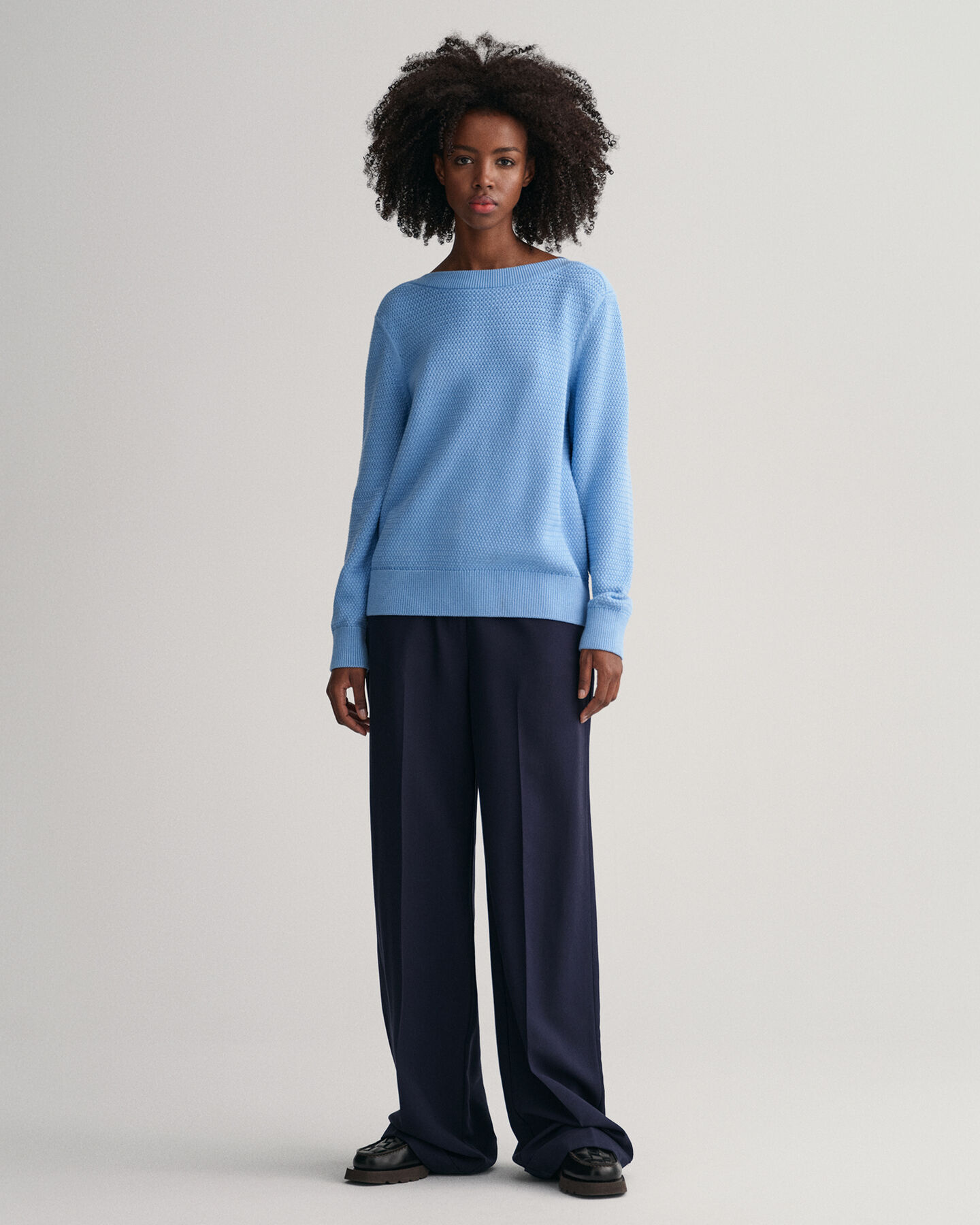 Kohopintainen puuvillaneulepusero, jossa venepääntie